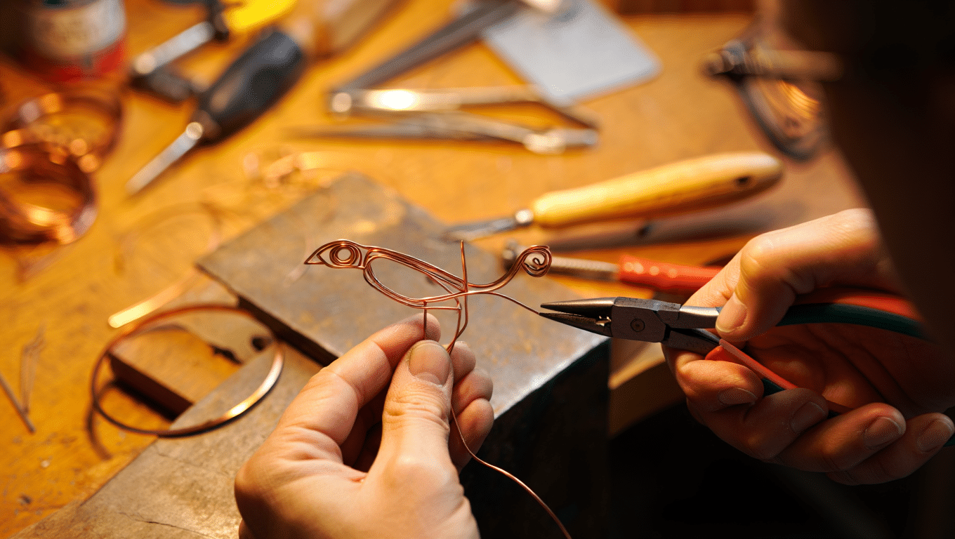 Sculpture fil de fer artiste — mains d'artisan travaillant le fil de cuivre dans un atelier